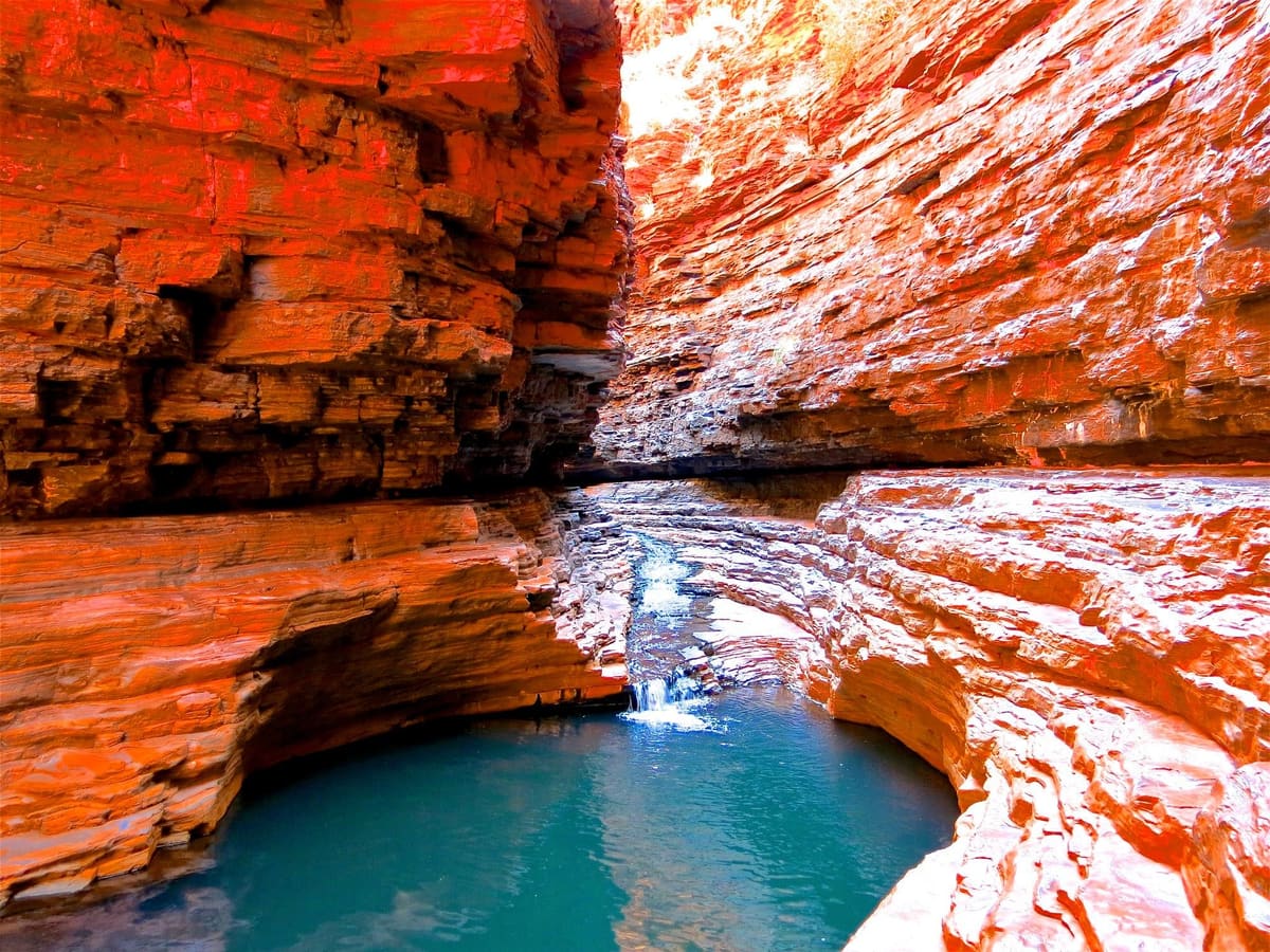 Kermit Pool in Hancock Gorge, orange slot-canyon walls above vivid turquoise water