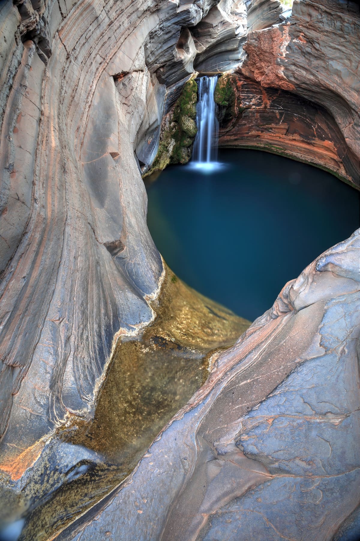Sculpted grey-white rock chutes feeding a turquoise pool with a small waterfall at Hamersley Gorge