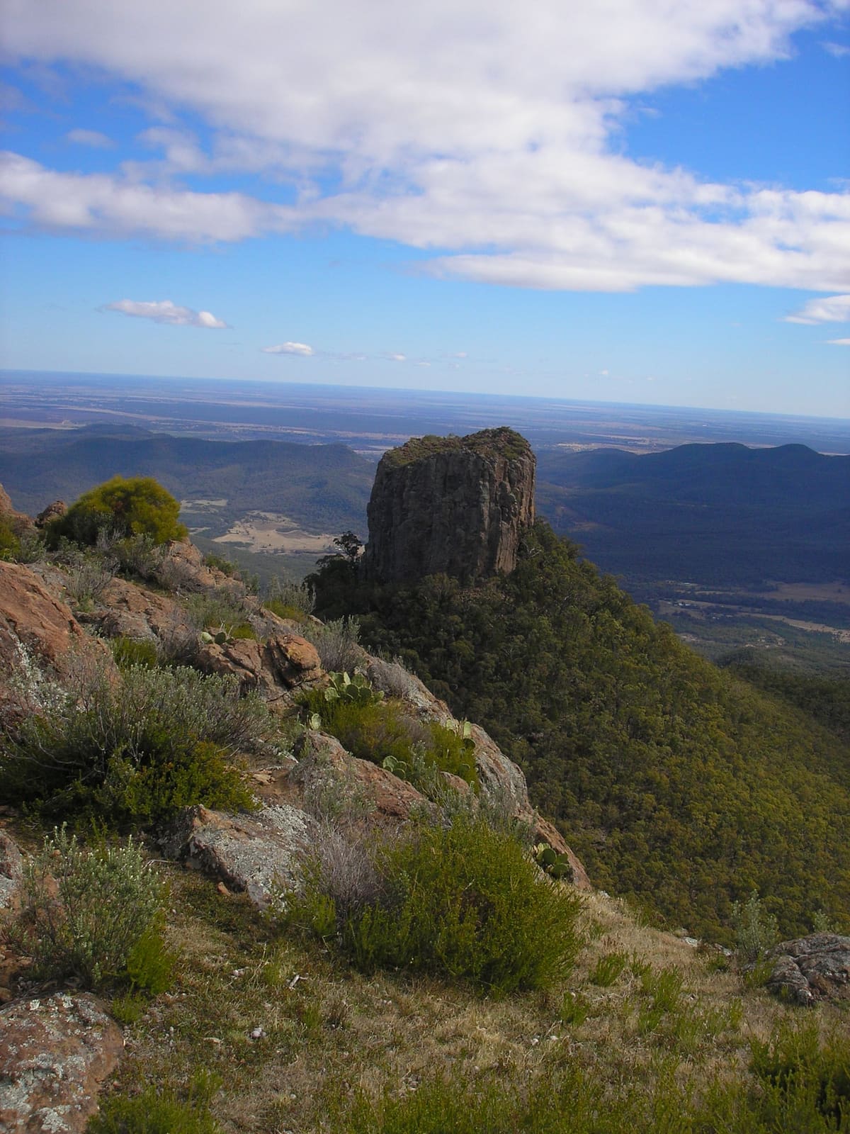 Rocky summit ridge with a rock pinnacle above vast inland plains