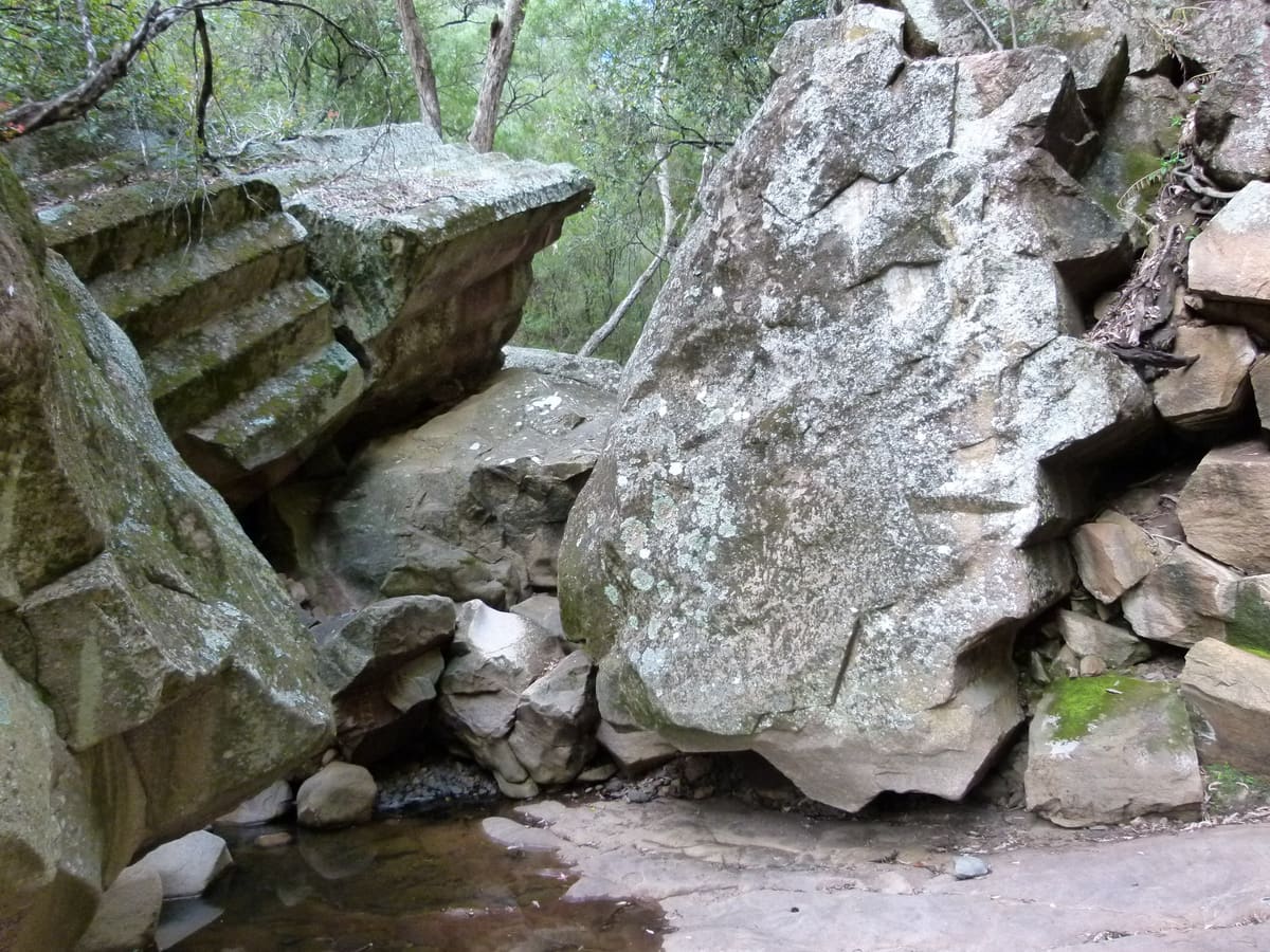 Fractured columnar basalt boulders and rubble at the base of a cliff