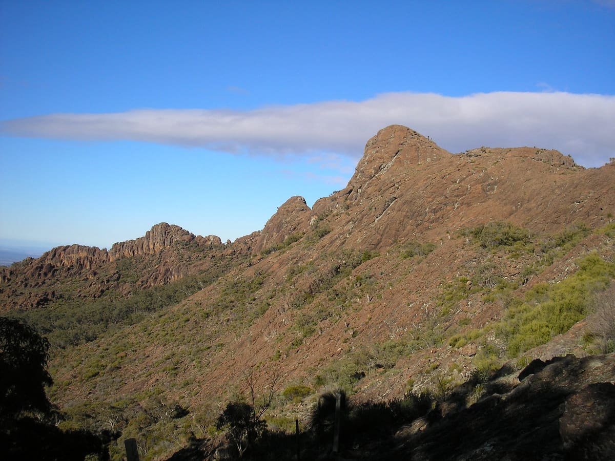 Rugged rocky ridgeline of Yulludundia Crater under a blue sky with lenticular cloud