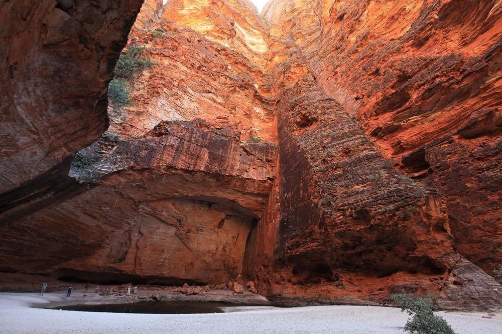 The natural amphitheatre of Cathedral Gorge in Purnululu National Park, towering red rock walls enclosing a still pool at the centre