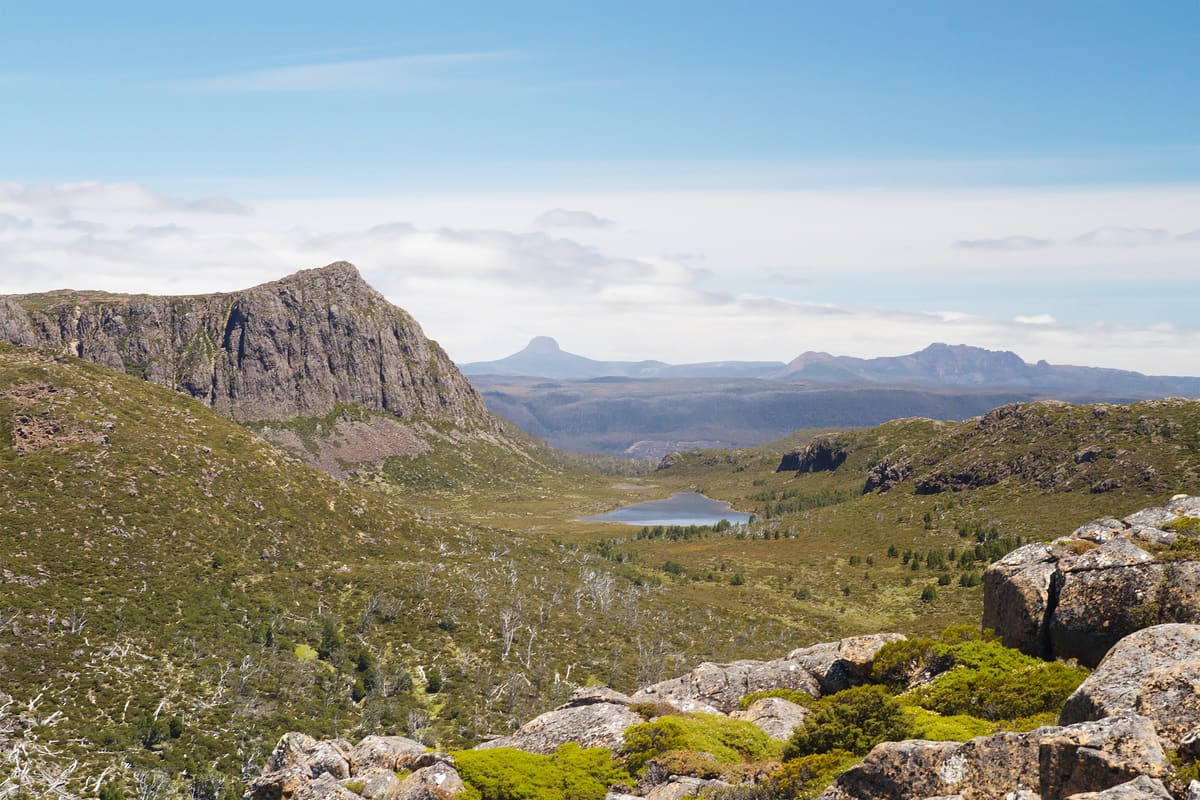 Rugged dolerite peak above a valley with a tarn, distant ranges on the horizon