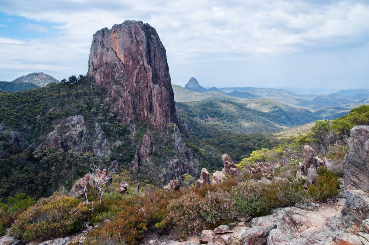 Sheer domed Crater Bluff above scrubby ridges and hazy ranges under cloudy sky